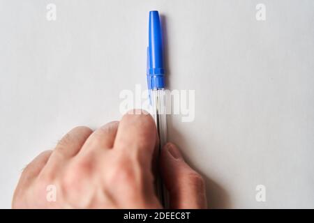 Penna di plastica blu in mano di giovane uomo su bianco sfondo Foto Stock