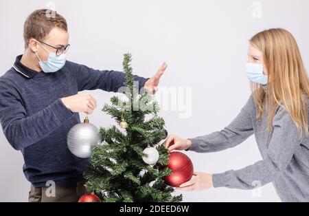 Coppia cercando di mantenere la distanza sociale mentre decorando l'albero di Natale Foto Stock