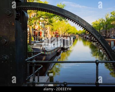 AMSTERDAM, PAESI BASSI - 01 MAGGIO 2018: Vista lungo il canale Brouwersgracht attraverso la ruota dentata con barche ormeggiate Foto Stock