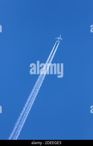 Aereo di linea a due motori per passeggeri commerciali in volo con controtagli / percorsi di condensazione contro il cielo blu Foto Stock