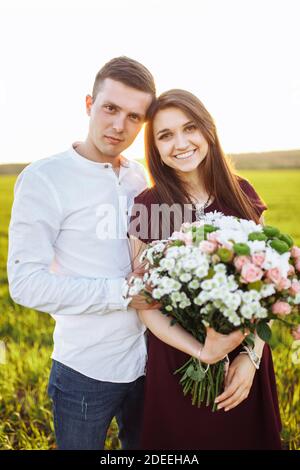 giovane coppia felice in amore, ragazza che tiene fiori, felice e godere l'una dell'altra azienda, pubblicità, Foto Stock