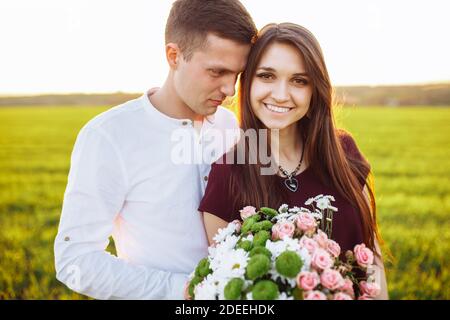 giovane coppia felice in amore, ragazza che tiene fiori, felice e godere l'una dell'altra azienda, pubblicità, Foto Stock