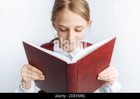 ragazzina scolastica che legge un libro, sfondo bianco, pubblicità, Foto Stock