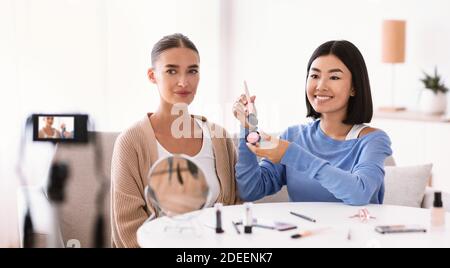 Donna asiatica facendo trucco per il suo modello Foto Stock