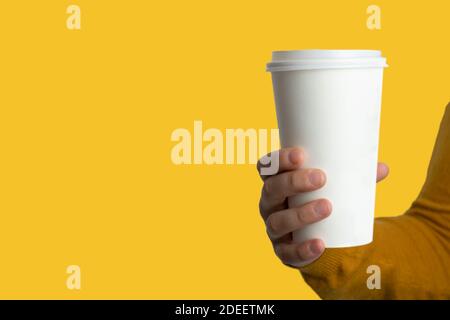 Donna mano che tiene una tazza di caffè di carta bianca su sfondo giallo isolato.Mockup , modello di banner con spazio di copia per il testo. Foto Stock