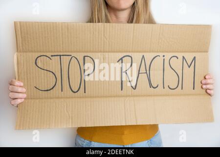 Giovane bella donna che tiene un poster di protesta con il testo Stop Racism.Politics e problemi sociali concetto, anti discriminazione razziale stile di vita. Foto Stock