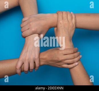 Donne irriconoscibili che tiene le mani che simboleggiano la togetherness, sfondo blu, tagliato Foto Stock