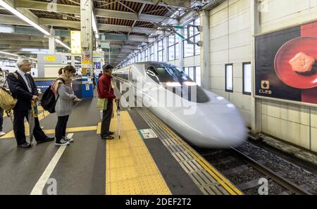 Treno superveloce giapponese che entra nella stazione ferroviaria di Hiroshima Foto Stock