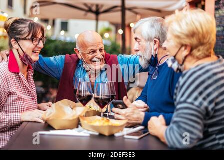 Sorridi con piacere gli anziani che bevono vino al bar ristorante all'aperto - nuovo concetto di vita normale con persone felici che si divertono insieme a mas. a faccia aperta Foto Stock