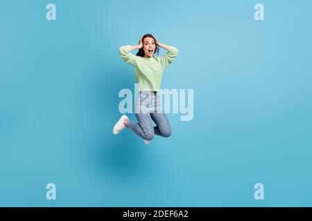 Foto a tutta lunghezza del corpo di una donna impressionata e scioccata studente salta tenendo le mani sulla testa isolato su vivido sfondo di colore blu Foto Stock