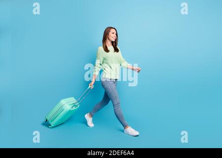 Ritratto fotografico di soddisfatta bella ragazza andando a viaggiare mantenere valigia che si fa sorridere isolato su uno sfondo di colore blu brillante Foto Stock