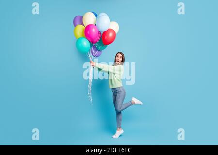 Lunghezza intera corpo dimensioni profilo laterale foto sorpreso impressionato femmina studente gridando in piedi typtoe tenendo palloncini sorridenti isolati su vibrante blu Foto Stock