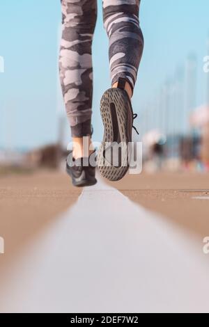 Atleta in forma che corre su strada. Runner shoes primo piano Foto Stock
