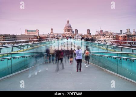 Un turista scatta una fotografia al Millennium Bridge, Londra, mentre tutti gli altri camminano oltre. Foto Stock