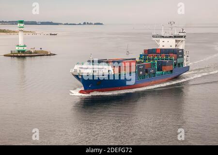 La nave container cargo nel Mar Baltico naviga oltre il faro vicino a Kiel, Schleswig-Holstein, Germania Foto Stock