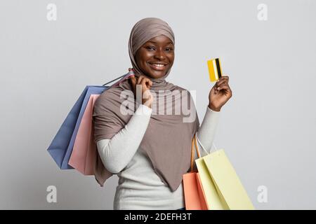 Sorridente donna musulmana nera in Hijab Holding Shopping Borse e. Carta di credito Foto Stock