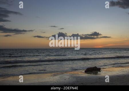 Onde che lambire sulla spiaggia al tramonto. Foto Stock