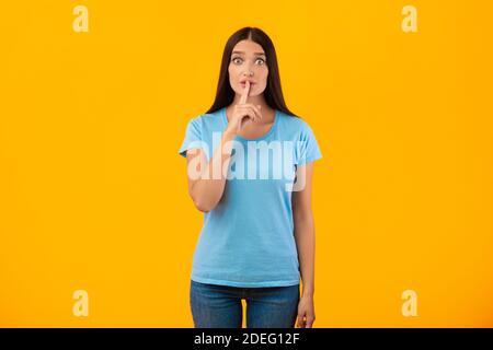 Donna che mette il dito sulle labbra, facendo segno di silenzio Foto Stock