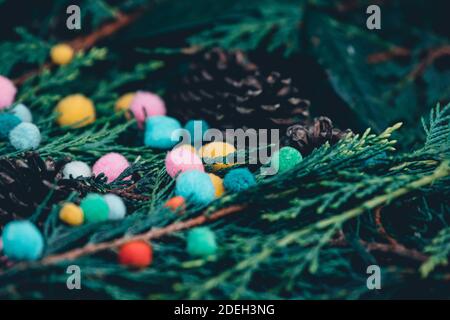 Vista closeup di alberi sempreverdi rami misti e pineconi con piccoli pomposi colorati, leggermente alternativo impostazione approccio di natale, morbido variato p Foto Stock