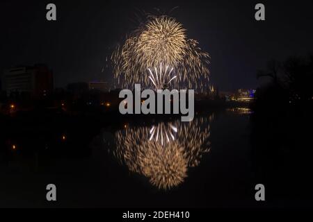 Festa di Capodanno colorati fuochi d'artificio scintillanti nel cielo di mezzanotte sulla città di Arad e Mures River, Romania Foto Stock