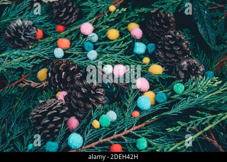 Vista closeup di alberi sempreverdi rami misti e pineconi con piccoli pomposi colorati, leggermente alternativo impostazione approccio di natale, morbido variato p Foto Stock