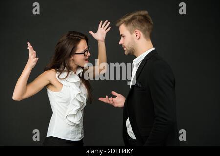 Disaccordo tra i colleghi. Donna emozionale e uomo combattono sfondo scuro. Conflitto professionale o personale. Risoluzione dei conflitti e professionalità sul posto di lavoro. Scarsa comunicazione aziendale. Foto Stock