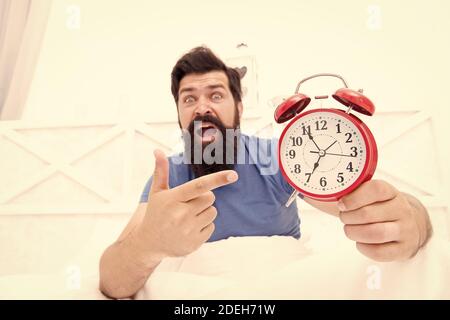 infelice uomo che punta alla sveglia. odio il rumore della sveglia. Uomo sveglio con retro sveglia che suona. Malato e stanco di insonnia. Sveglia al mattino. Tempo e concetto di invecchiamento. Foto Stock