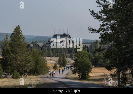 I visitatori su un sentiero con lo storico Old Faithful Inn dietro nel Parco Nazionale di Yellowstone, Wyoming, Stati Uniti. Foto Stock