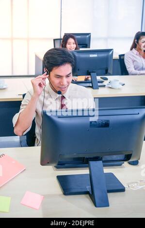 Giovane agente del servizio clienti uomo con cuffie e computer che lavorano in ufficio. Concetto di operatore professionale. Foto Stock