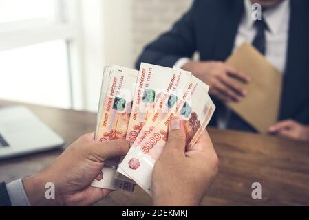 Uomo d'affari che conta un migliaio di banconote russe in denaro date dopo aver raggiunto un accordo - prestiti finanziari, tangenti e concetti di corruzione Foto Stock