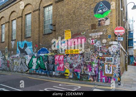 Poster Graffiti su un muro a Buxton Street, Spitalfields, Londra E1 Inghilterra, Regno Unito Foto Stock