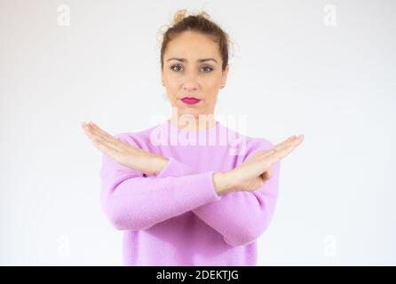 Giovane bella donna che indossa un maglione casual su sfondo bianco espressione di rifiuto che attraversa le braccia facendo segno negativo, faccia arrabbiata Foto Stock