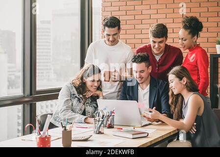 Gruppo di giovani interior designer che guardano lo schermo del computer portatile, brainstorming e condividere idee del loro collega lavoro di progetto in una riunione, hap Foto Stock