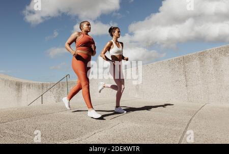Due donne che fanno jogging insieme. Le amiche sportive indossano la corsa al mattino. Foto Stock