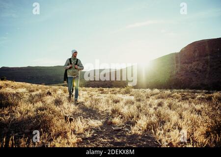 Paesaggio di adolescenti che camminano indossando zaini che camminano attraverso la foresta lusciosa Foto Stock