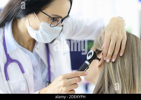 Otorhinolaringologo che guarda i pazienti all'orecchio con otoscopio in clinica Foto Stock