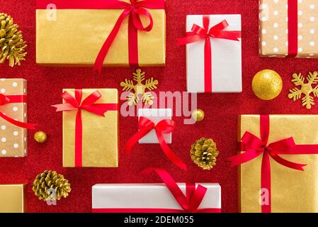 Set di confezioni regalo per Natale e Capodanno con oggetti decorativi su sfondo colorato rosso scintillante - vista dall'alto, idea creativa di posa piatta Foto Stock