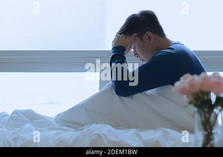 Una persona seduta e sentendosi depressa sul letto. Concetto di depressione e solitudine. Foto Stock