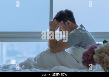 Una persona seduta e sentendosi depressa sul letto. Concetto di depressione e solitudine. Foto Stock