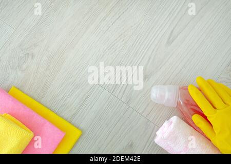 Strumenti di pulizia rosa: Stracci, spugne, liquido per lavastoviglie, mani in guanti di gomma su fondo di legno chiaro, vista dall'alto. Detergenti e accessori per la pulizia Foto Stock