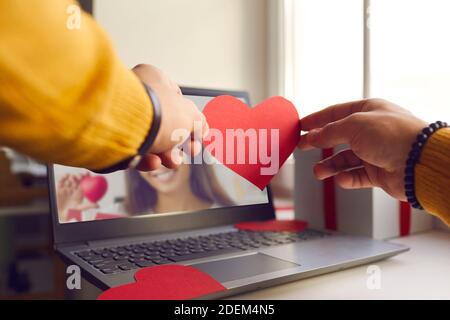 Uomo irriconoscibile che mostra cuore di San Valentino alla sua ragazza in romantico data online in blocco Foto Stock