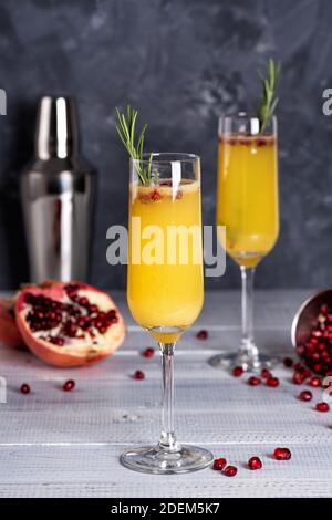 Cocktail Mimosa con succo d'arancia e champagne. Festa di Capodanno o di compleanno. Melograno e rosmarino Foto Stock