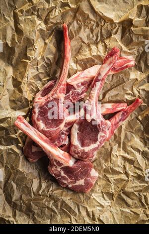 Tagliate a fette le costolette di agnello crudo su carta da forno. Vista dall'alto. Foto Stock