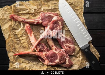 Tagliate a fette le costolette di agnello crudo su carta da forno. Vista dall'alto. Foto Stock