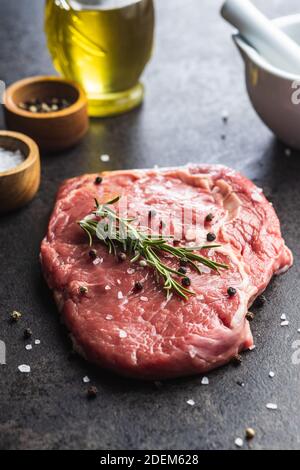 Bistecca di ribeye crude tagliata su un tavolo da cucina nero. Foto Stock