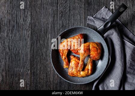 Quarti di zampa di pollo serviti su una padella su sfondo di legno, vista dall'alto, primo piano Foto Stock