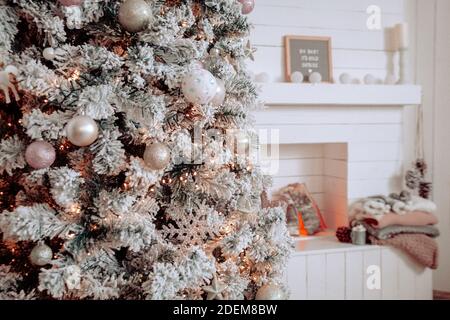 Accogliente soggiorno con composizione invernale. Coperte accanto a un camino bianco, pinecones, tazza rustica. Interni cottage bianchi. Bambino è freddo fuori segno. Foto Stock