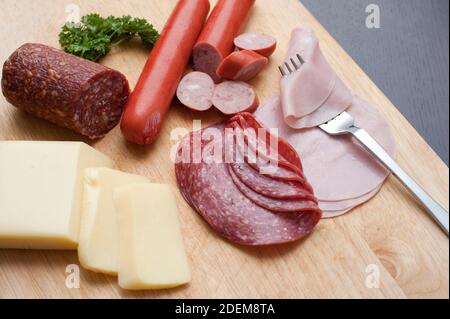 Ricca colazione tradizionale tedesca con salumi assortiti, salumi e carni fredde, accompagnati da fette di formaggio servite su un trito di legno Foto Stock