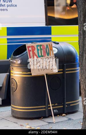 Protesta anti-lock-down, Londra, 28 novembre 2020. Un cartello di protesta scartato di un protestante arrestato si appoggia contro un cestino pubblico dei rifiuti. Foto Stock