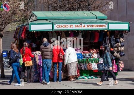 Londra, UK, 1 aprile 2012 : turista che acquista un regalo di ricordo ad una bancarella del mercato di strada che vende le borse ed gli accessori di cuoio che hanno mangiato il viaggio popolare Foto Stock